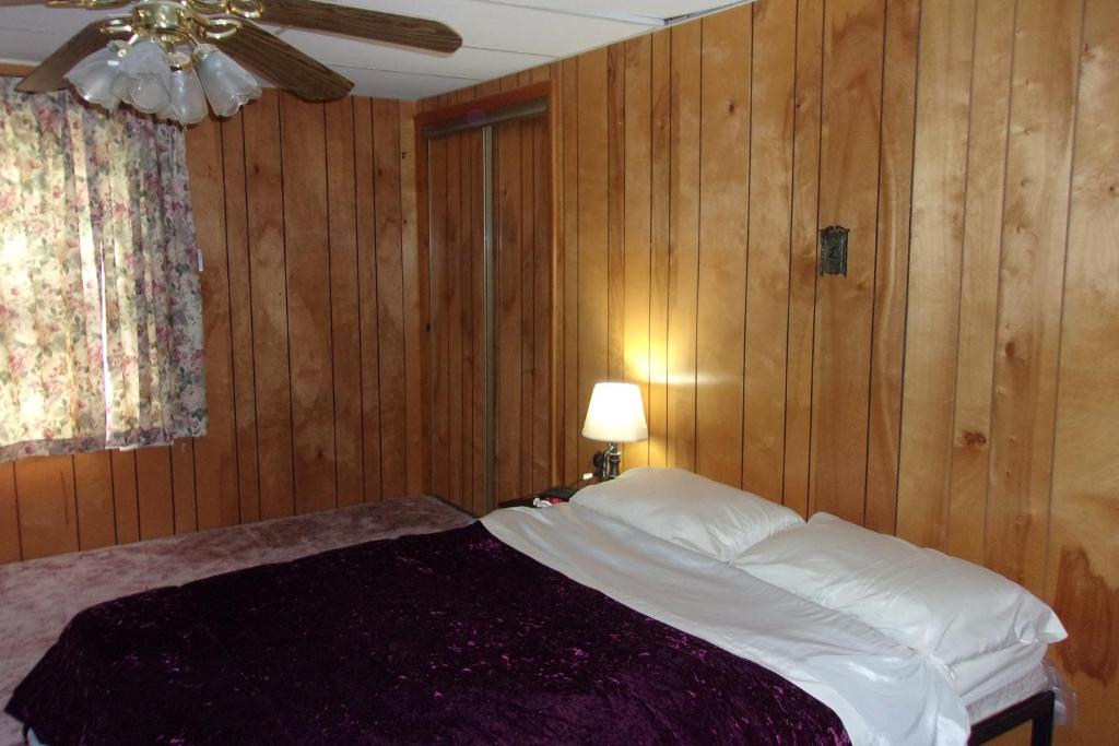 Schlafzimmer mit einem Bett mit Holzwänden und einer Decke in der Unterkunft NiceShortStayMassena in Massena