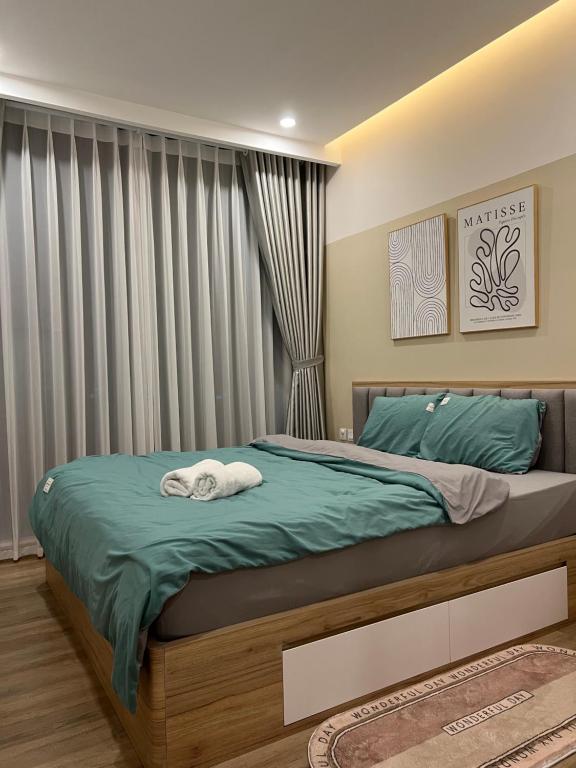 a bedroom with a bed with green sheets and a window at LaLisa homestay Ecopark- Căn hộ thoải mái & ấm cúng Van giang Hung Yen in HÆ°ng YÃªn