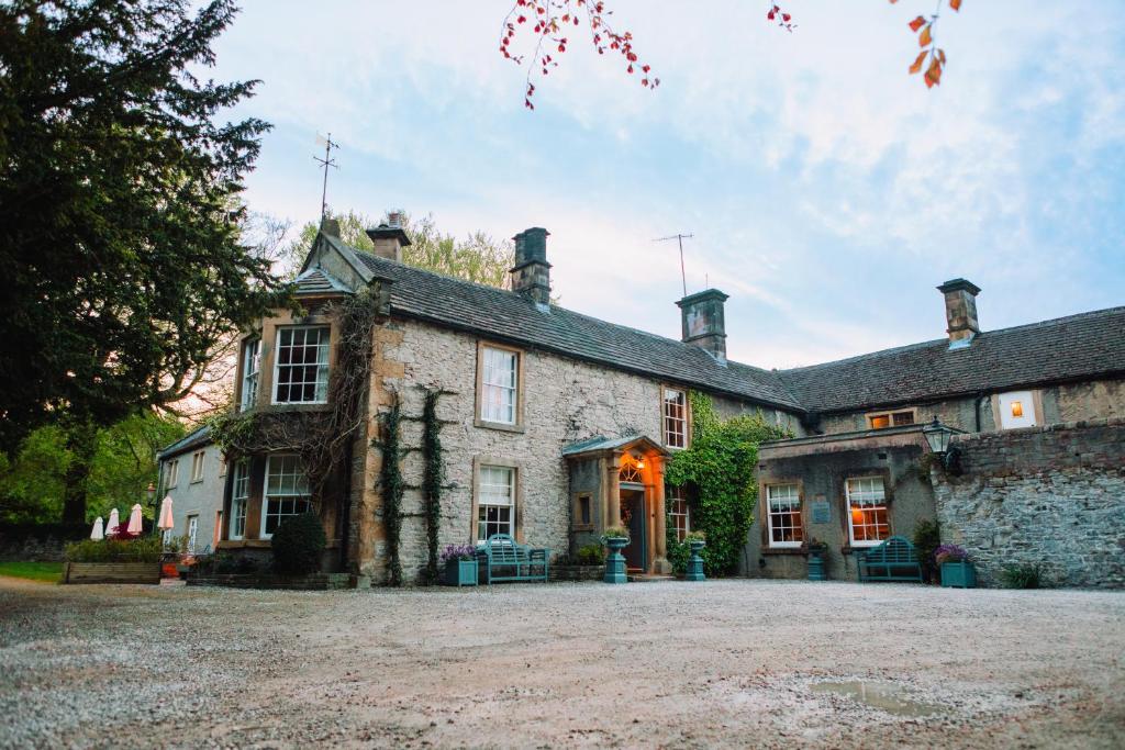 an old stone house with a large driveway at Rafters at Riverside House Hotel in Bakewell