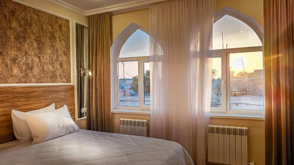 a bedroom with a bed and two windows at Hotel Bankir Khiva in Khiva