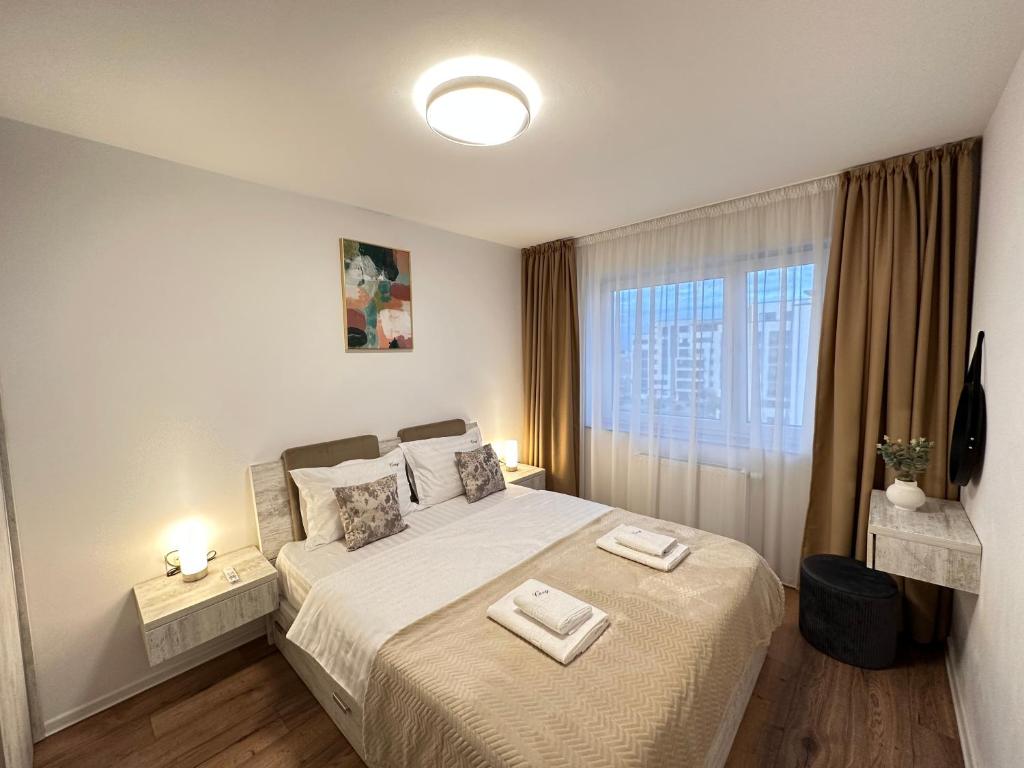 a bedroom with a bed with two towels on it at Deluxe Cozy Apartments - Coresi Mall #Brasov in Braşov