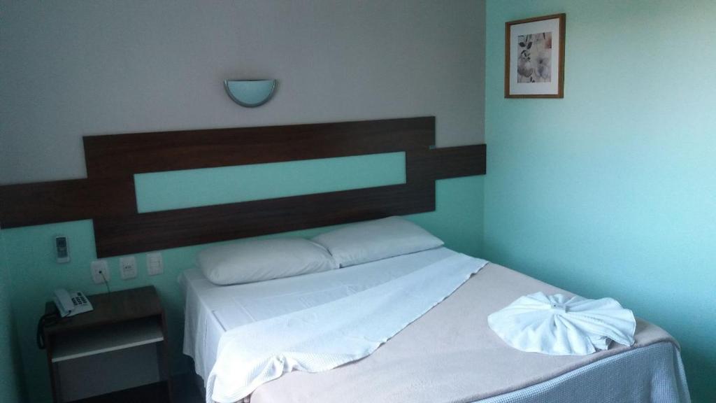 Schlafzimmer mit einem Bett mit einem Kopfteil aus Holz in der Unterkunft Hotel Boa Vista in Chapecó