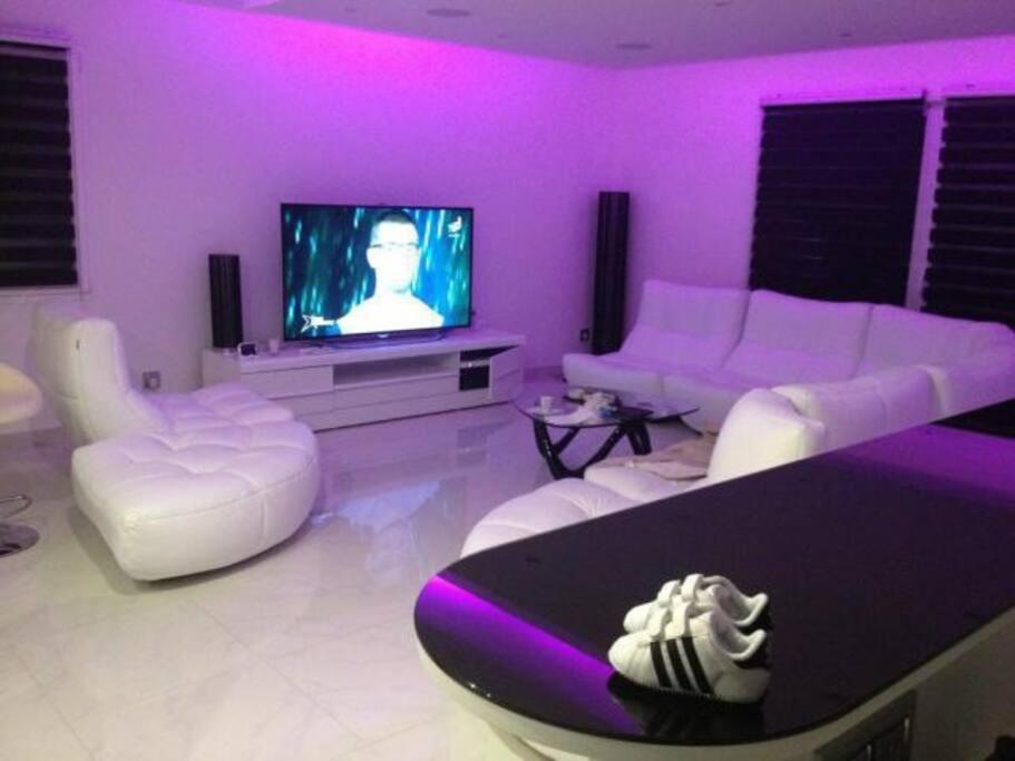 uma sala de estar roxa com mobiliário branco e uma televisão em Magnifique villa avec piscine chauffée em Cauroy-lès-Hermonville