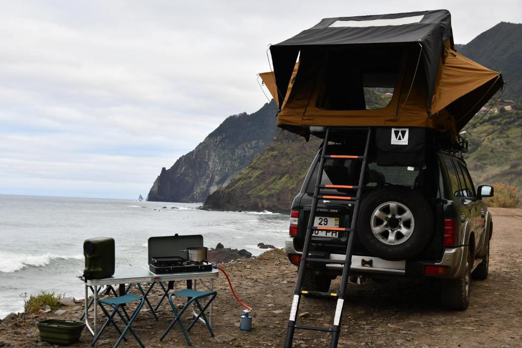 a jeep with a camper on top of it next to the ocean at Overland Madeira in Santana