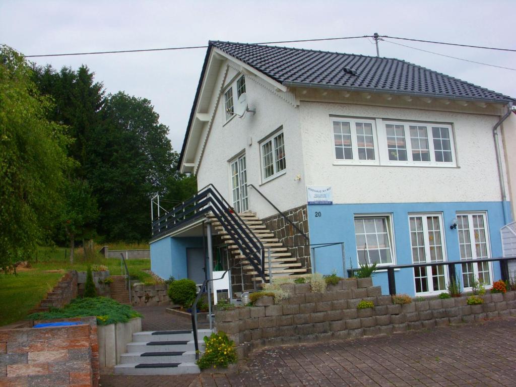 een wit en blauw huis met een trap aan de voorkant bij Ferienhaus Am See in Wadern