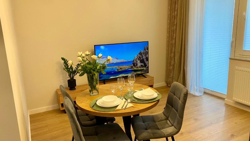 a dining room with a table with chairs and a tv at Apartament GREEN CROWNS in Płock