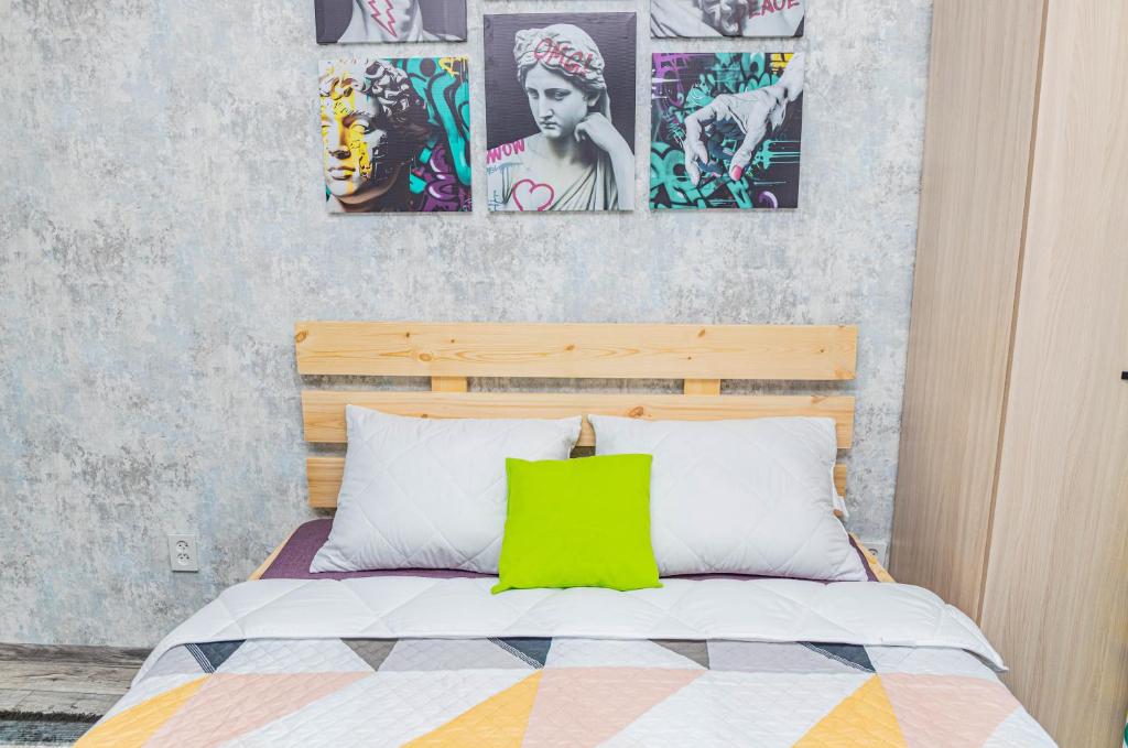 a bedroom with a bed with a green pillow on it at YourHouse на Си Синхая 22 близко к Меге in Almaty