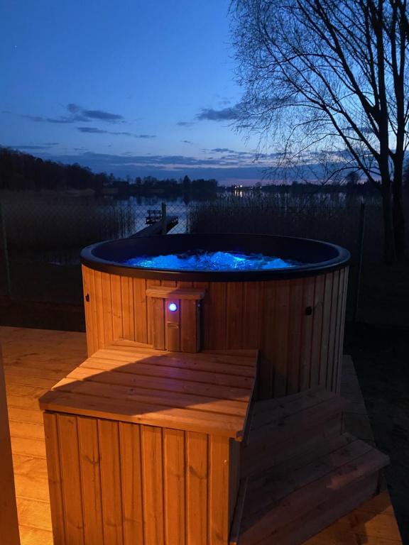 bañera de hidromasaje en una terraza de madera con cielo nocturno en Bajkowa Przystań domki nad jeziorem, 