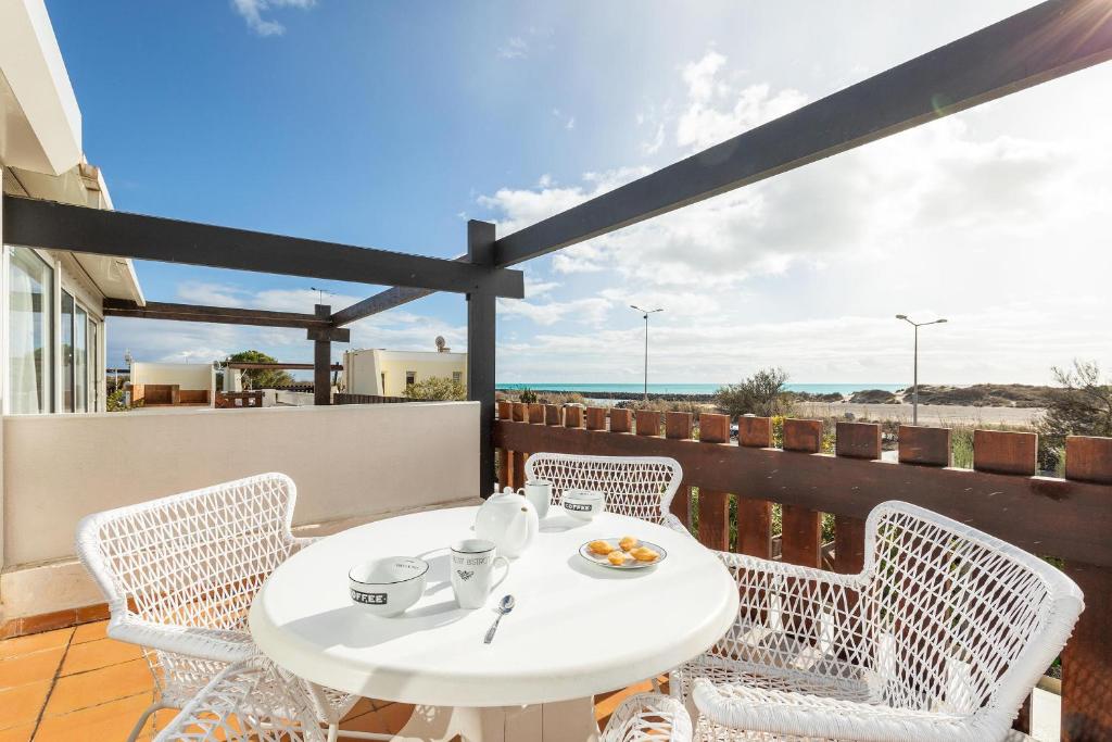- une table et des chaises blanches sur un balcon donnant sur la plage dans l'établissement Village Naturiste R4N - La Villa Aphrodite Sea View, au Cap d'Agde