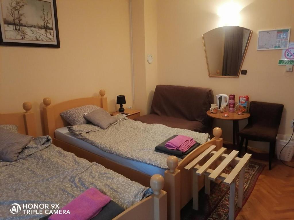 Habitación con 2 camas, silla y mesa. en Soba Sekulić, en Sombor