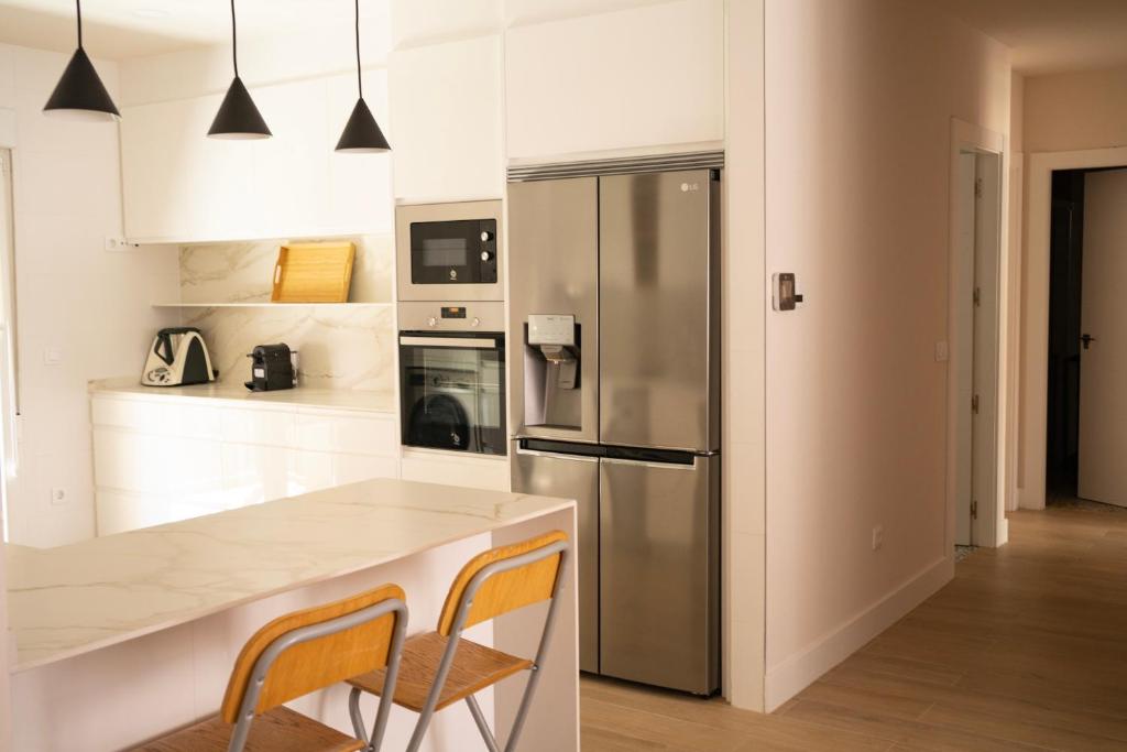 eine Küche mit einem Kühlschrank aus Edelstahl und 2 Stühlen in der Unterkunft Apartamento NUEVO en el centro de LEON in León
