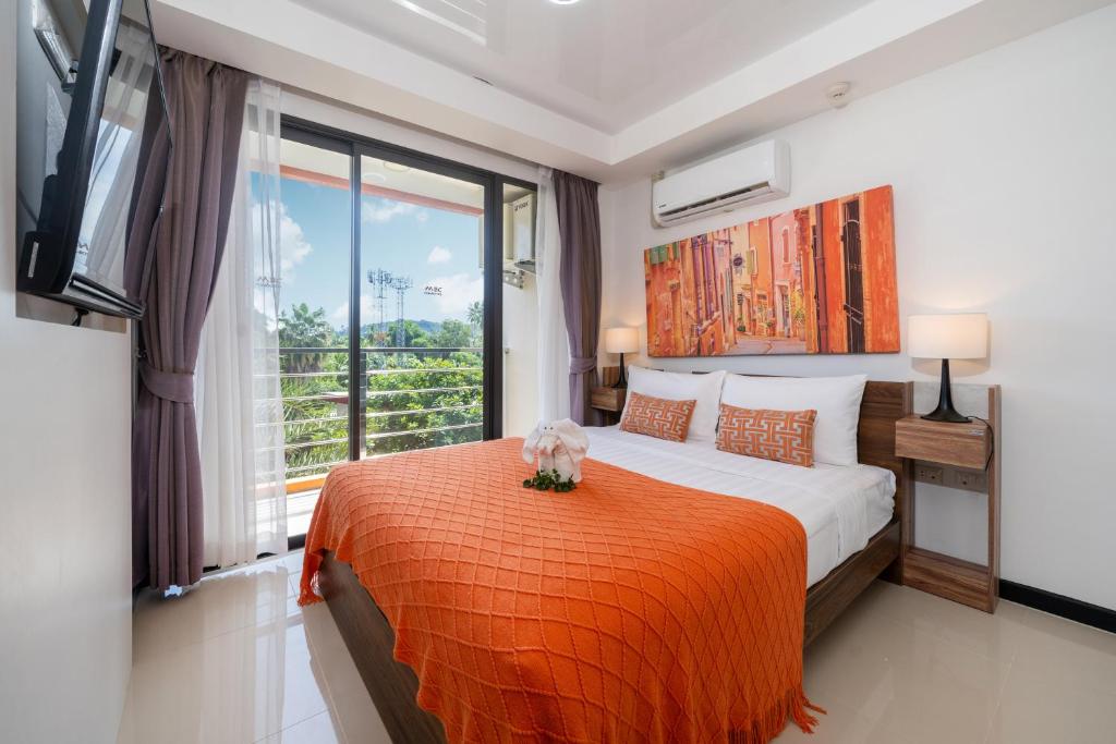 a bedroom with a bed with an orange blanket and a window at Tropical Living Mai Khao Beach in Ban Bo Sai Klang