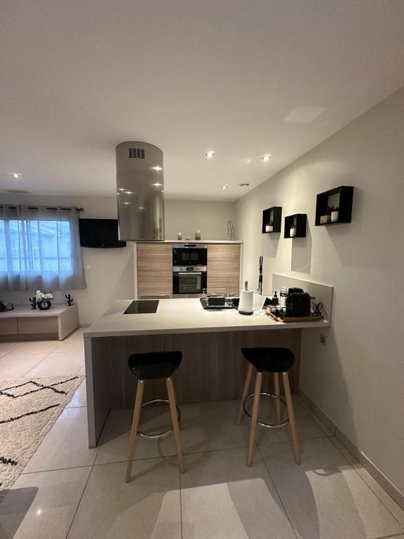 une cuisine avec un comptoir et deux tabourets de bar dans l'établissement Maison d'hôtes chic à Beauzelle, à Beauzelle