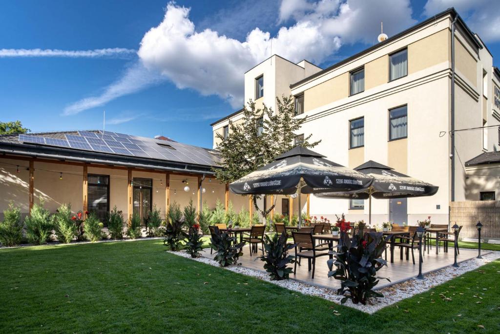 a patio with tables and umbrellas in front of a building at Inter Hotel in Debrecen