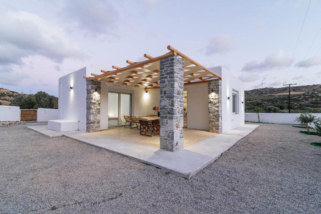 a white house with a stone pillar and a table at Nikkon summer house in Matala