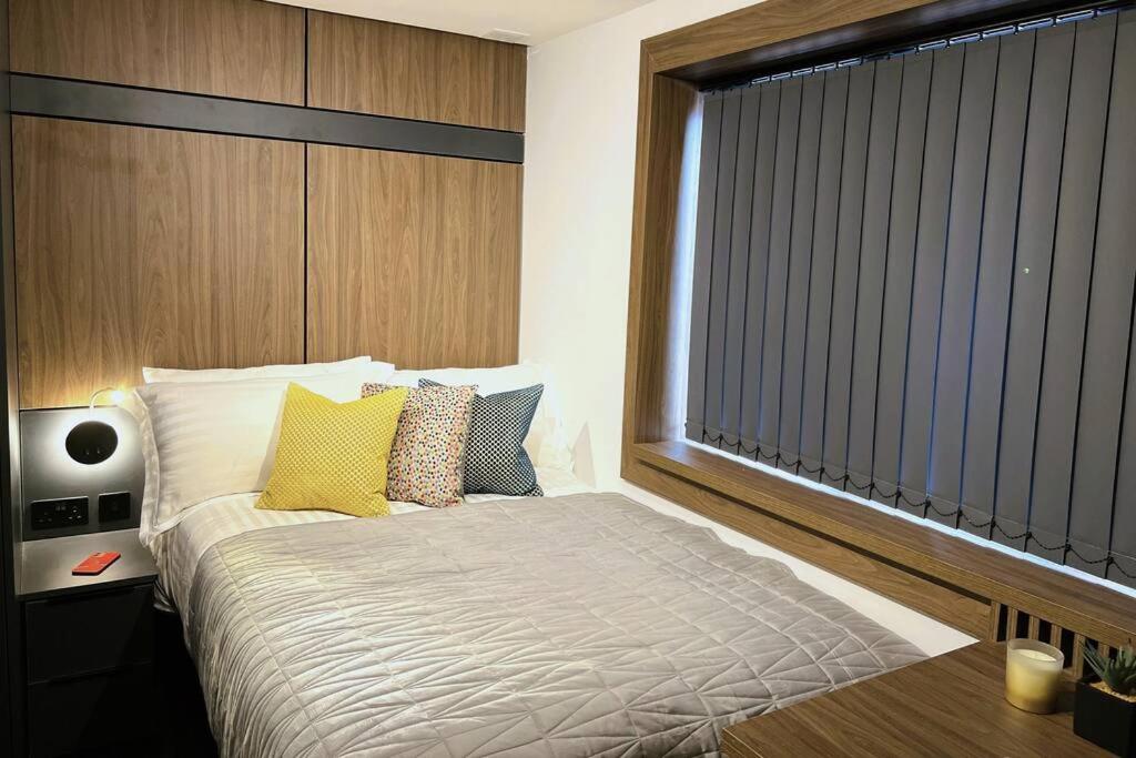 ein Schlafzimmer mit einem Bett mit gelben Kissen und einem Fenster in der Unterkunft Lovely 1 Bed Studio (3B) near Royal Infirmary and DMU in Leicester
