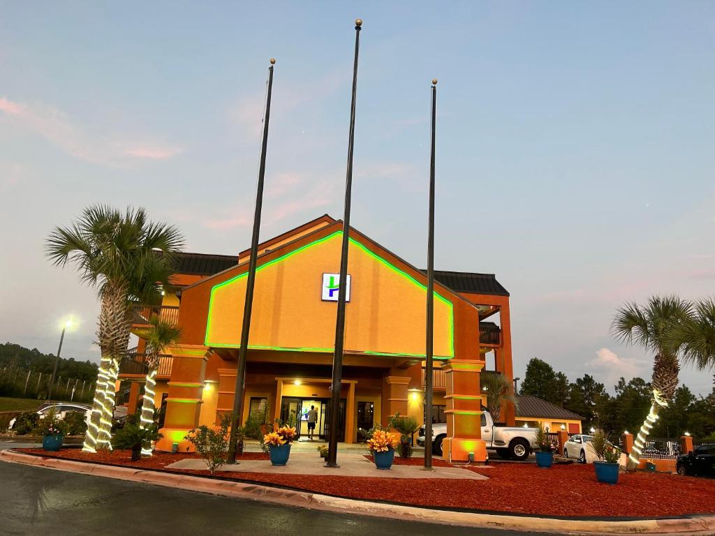 a building with palm trees in front of it at Home Town Inn & Suites in Crestview