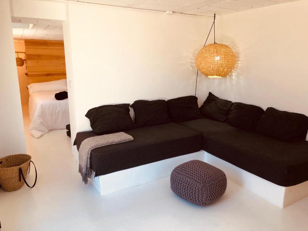 ein Wohnzimmer mit einem schwarzen Sofa und einem Bett in der Unterkunft Casa Luz in El Pozo de los Frailes