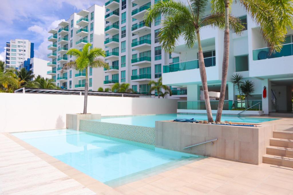 una piscina con palmeras frente a un edificio en Magico Apartamento Frente al Mar 4 Habitaciones O62, en Coveñas