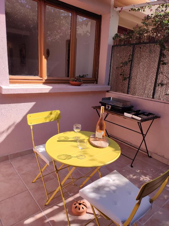 - une table jaune avec deux chaises et une bouteille dans l'établissement Charmant Studio Lavandou - 500m plage, au Lavandou