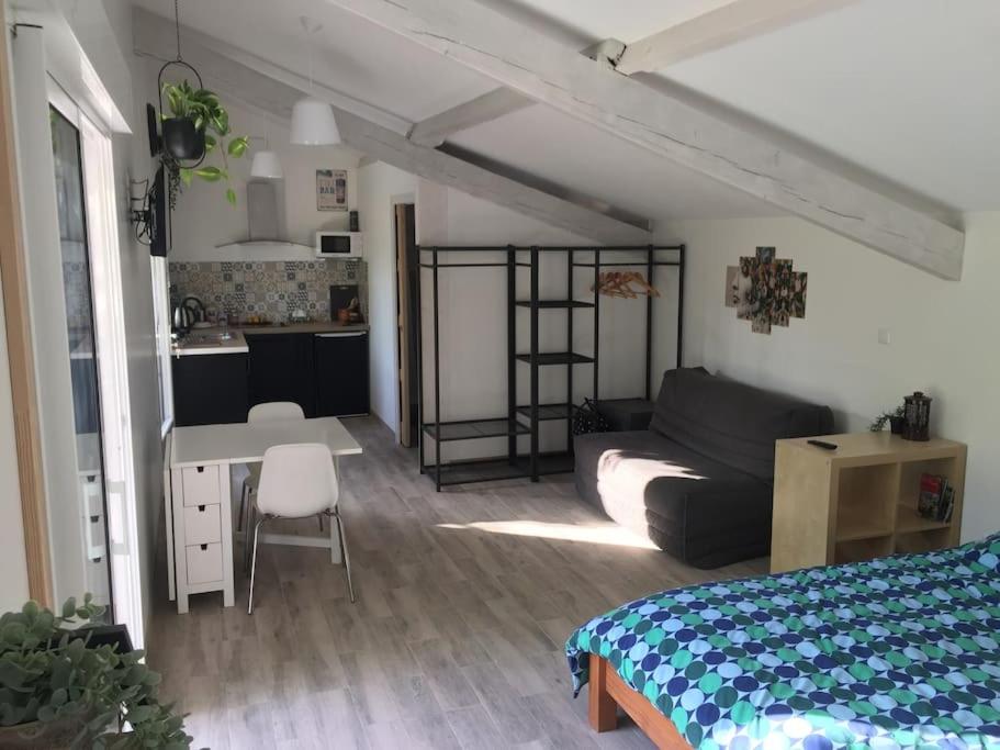 a bedroom with a bed and a desk and a kitchen at studio avec jardin en campagne in Le Thor