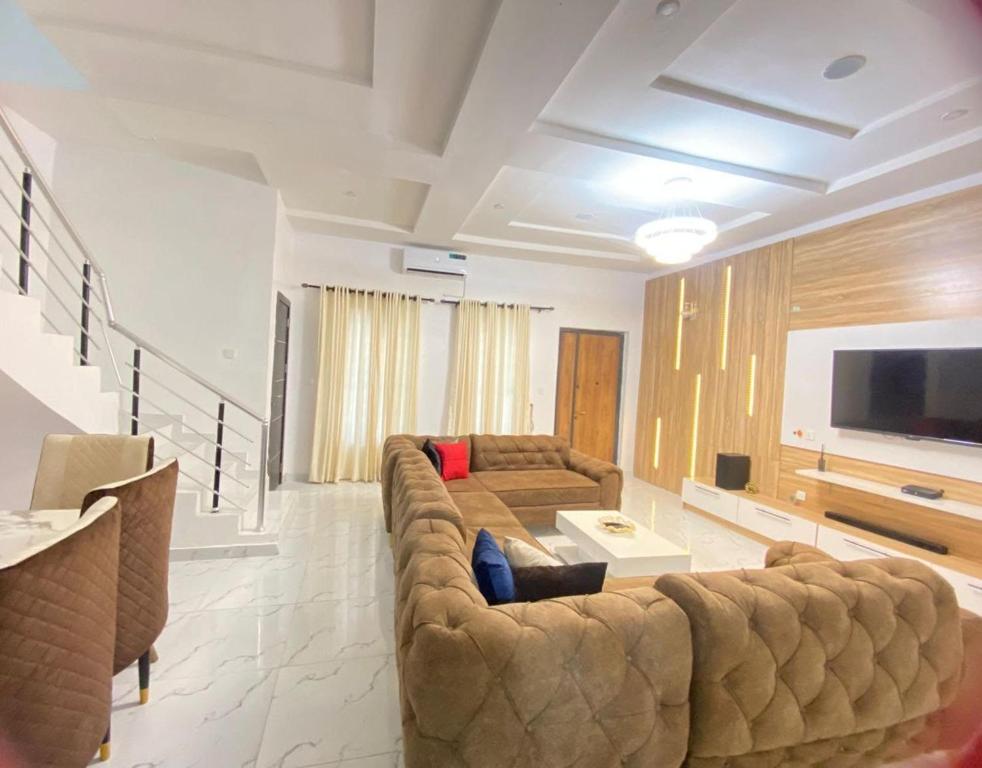 a living room with a large couch and a flat screen tv at Luxury 4 bedroom shared shortlet apartment lekki in Lagos