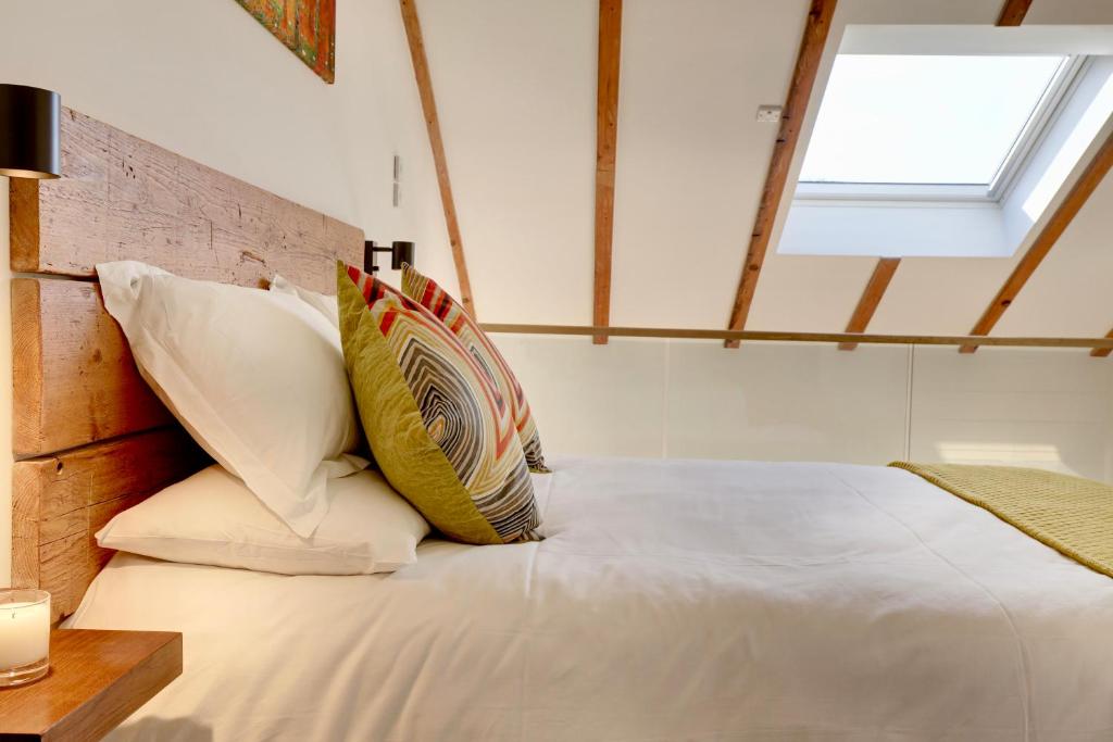 um quarto com uma cama com almofadas e uma janela em The Owl Barn Wiltshire - Flint em Swindon