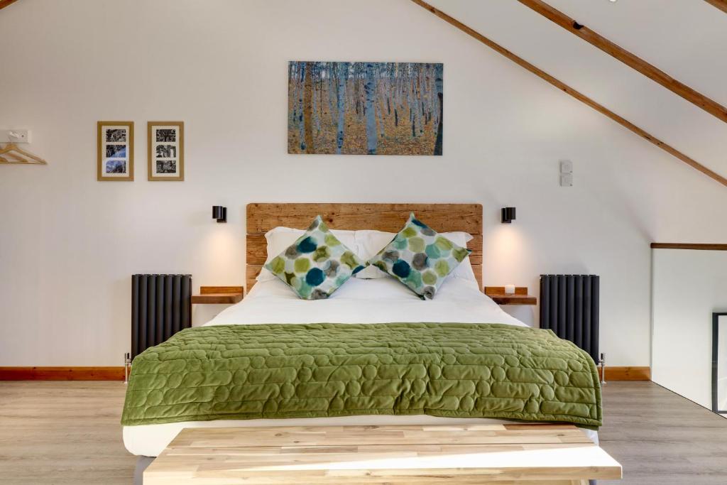 a bedroom with a large bed with a green blanket at The Owl Barn Wiltshire - Slate in Swindon