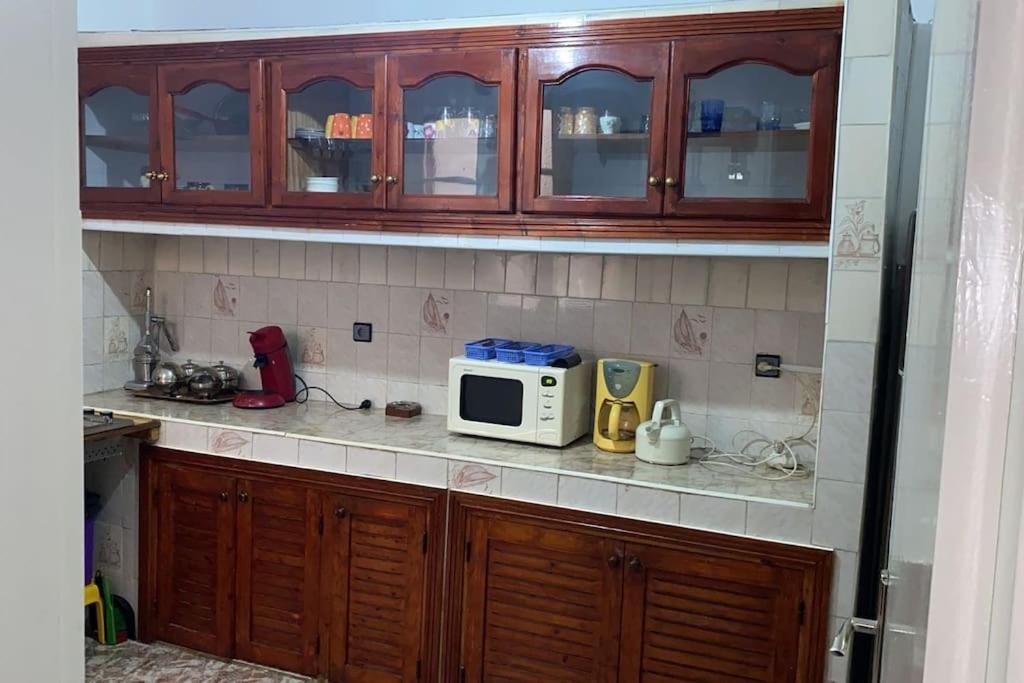 - une cuisine avec des placards en bois et un four micro-ondes dans l'établissement Appartement spacieux, à Casablanca