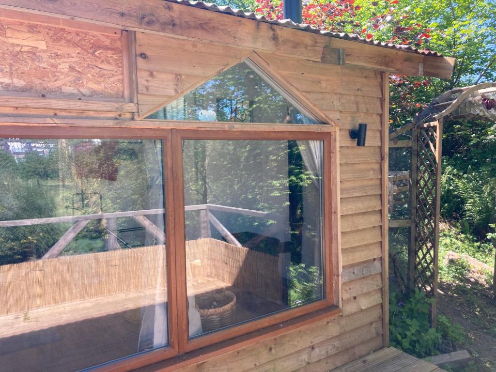 a wooden greenhouse with a window in a garden at Honey Bee Cabin in Llandysul