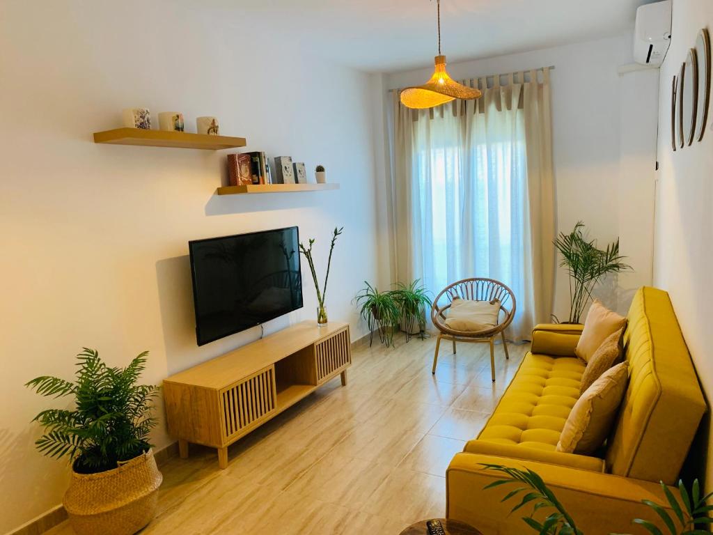 un soggiorno con divano giallo e TV di Apartamento Las Minas a Baeza