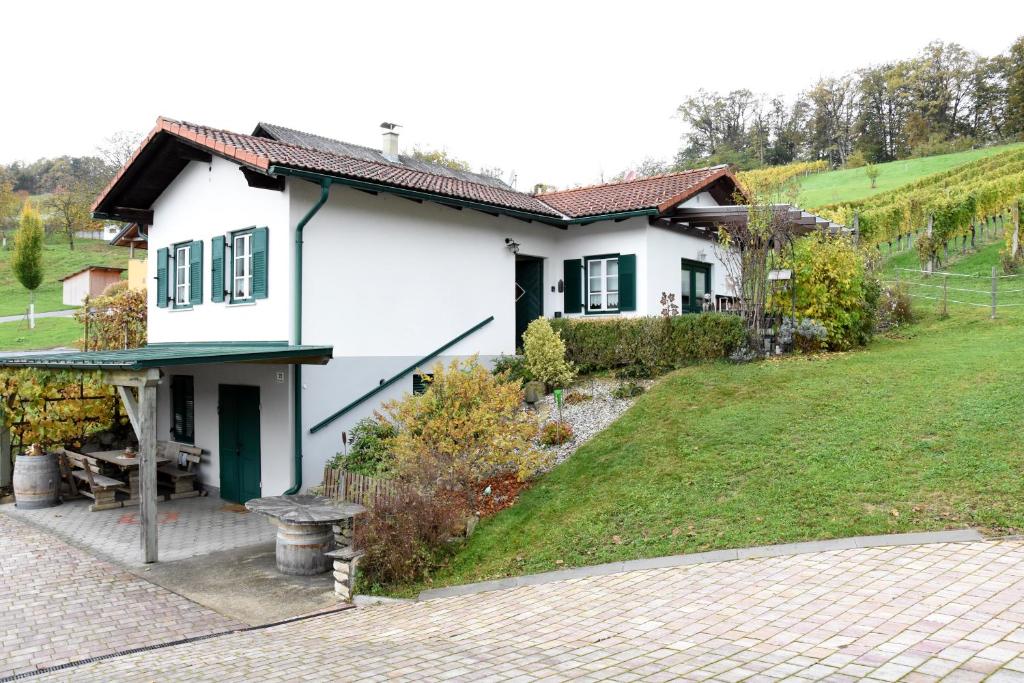 ein kleines weißes Haus mit einem Rasenplatz in der Unterkunft Wein & Wohnen MATZL - Ferienwohnung in Fürstenfeld