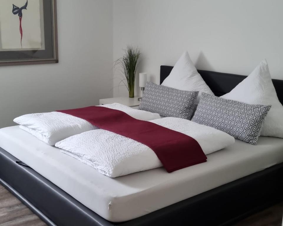 a bed with white and red blankets and pillows at Gemütliche Oase - Geräumige Unterkunft in Sarreguemines