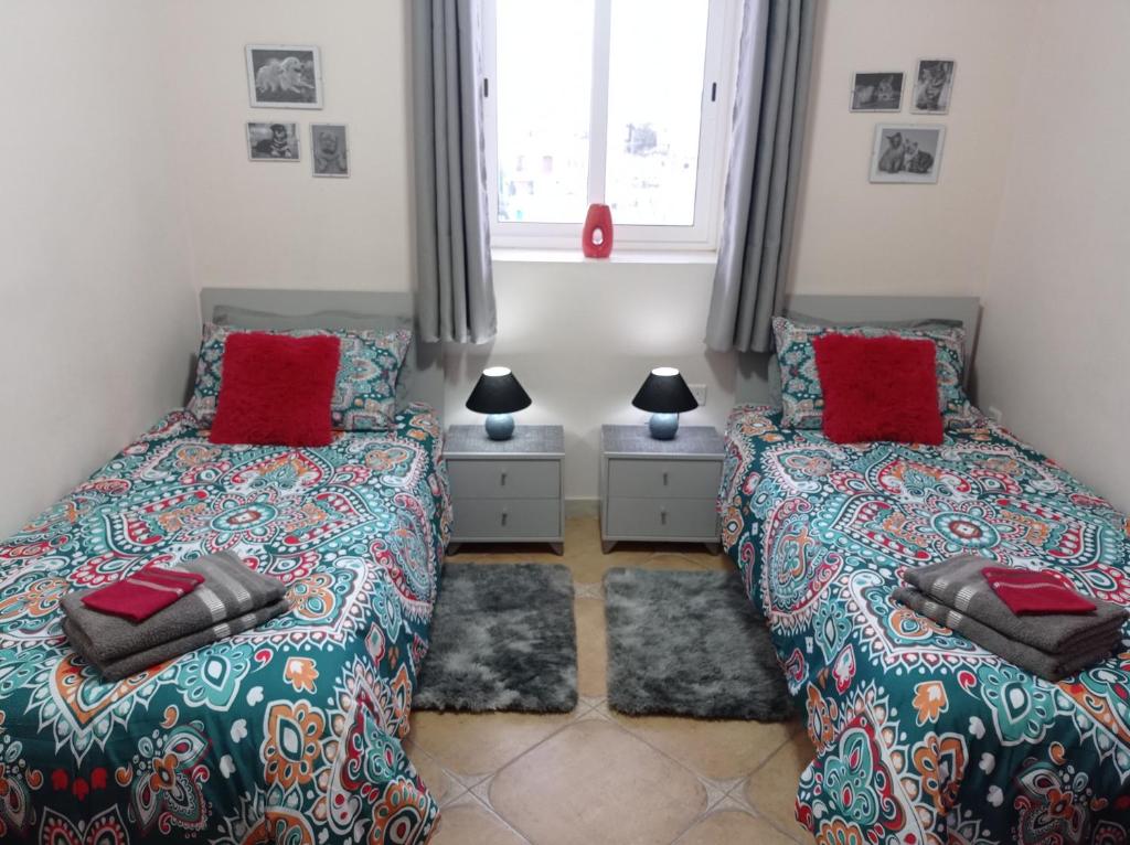 1 dormitorio con 2 camas y almohadas rojas en "Joseph 2" Stylish corner flat with open views, just 5km from the beach, en Siġġiewi