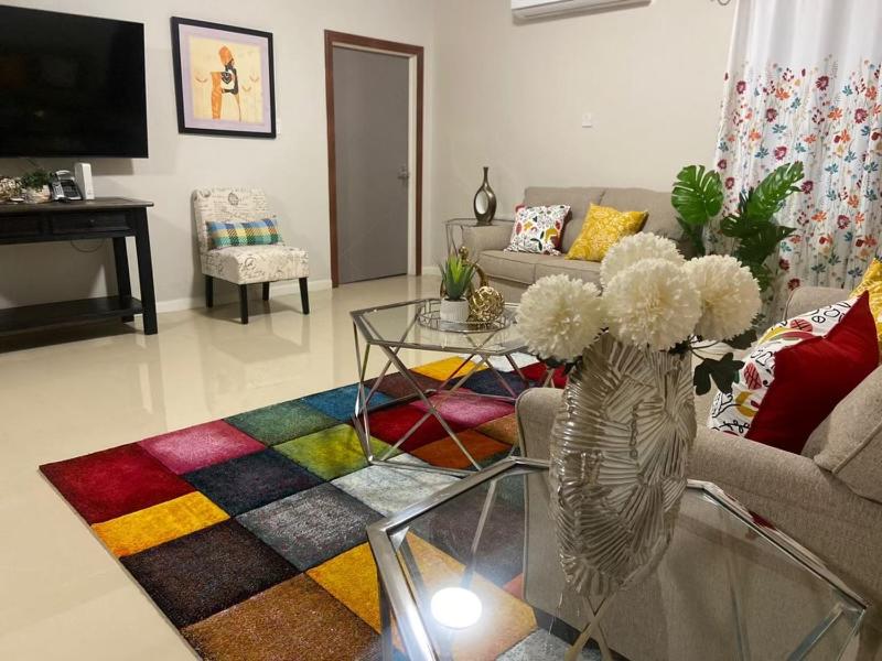 a living room with a couch and a vase with flowers at Victory Luxury Apartments in Montego Bay