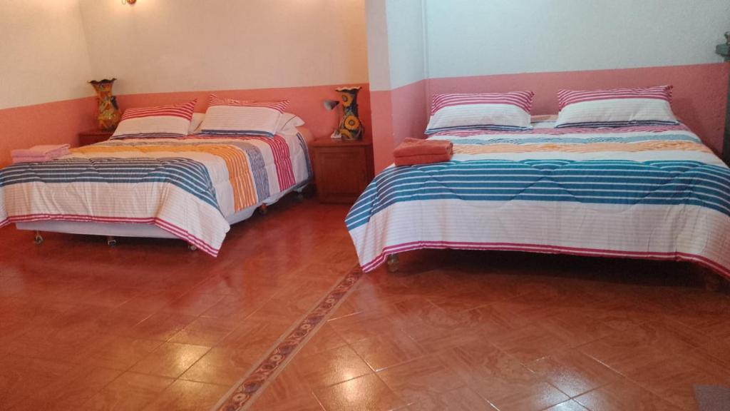 two beds sitting in a room with wood floors at Olivos Habitación cuádruple in Tequisquiapan