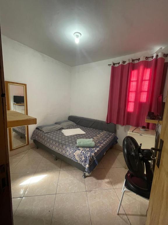 Habitación pequeña con cama y ventana roja. en Renan suítes, en Arraial do Cabo