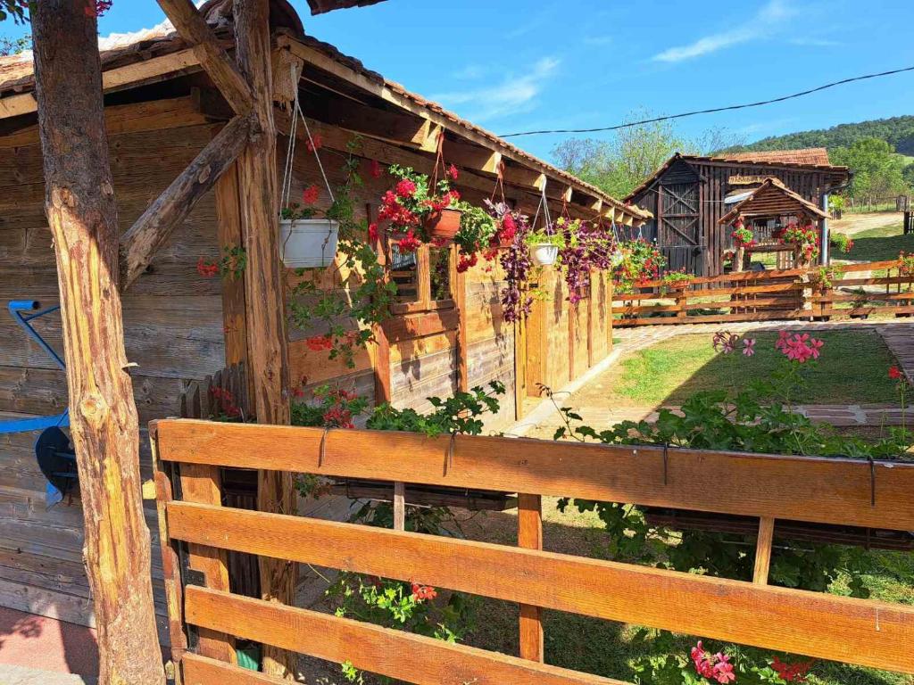 Una casa de madera con flores a un lado. en Pavlovica konaci, en Kotraža