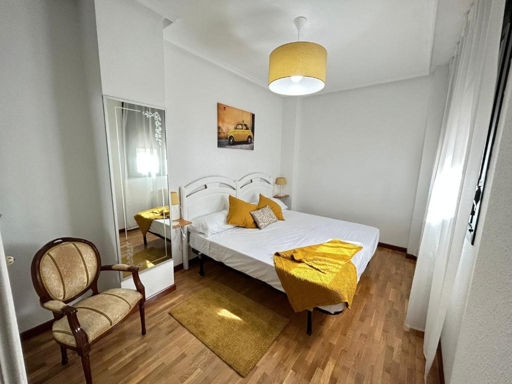 una camera con un letto bianco e una sedia di El paraíso de Lita - a 10 min del centro con WiFi a Oviedo