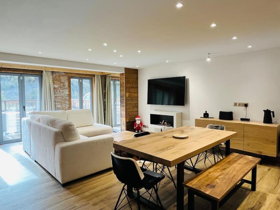 uma sala de estar com um sofá branco e uma mesa de madeira em Coup de coeur Montagnard - 2 chambres - Cheminée - Garage em Isola 2000