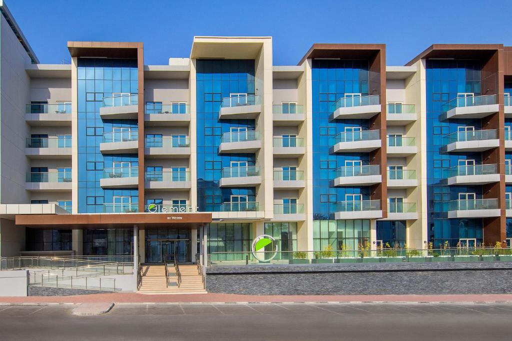 ein Apartmenthaus mit blauen Fenstern auf einer Straße in der Unterkunft Element Dubai Airport in Dubai