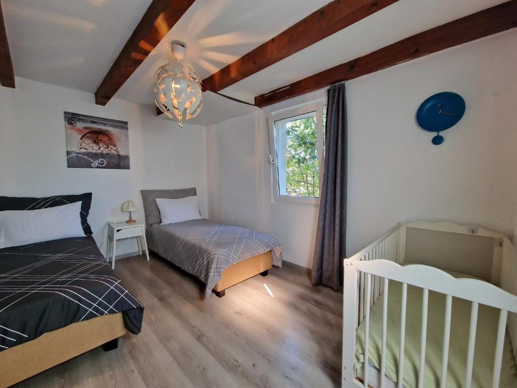 - une chambre avec 2 lits, un lit bébé et une fenêtre dans l'établissement Maison villageoise, à Collombey