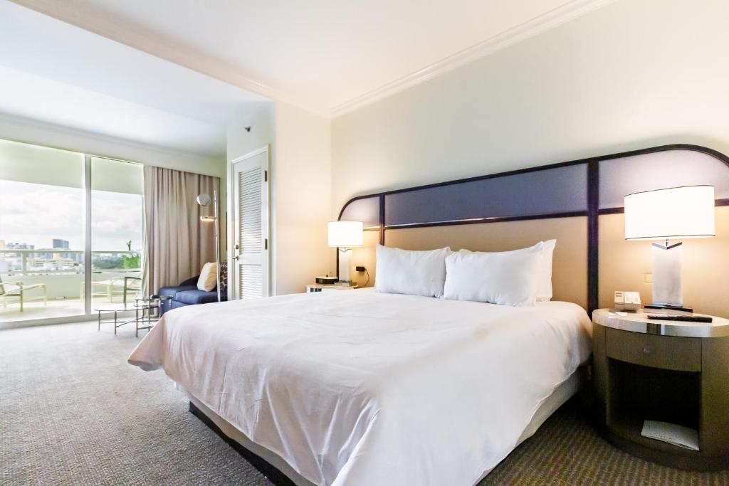 a hotel room with a large white bed and a balcony at Fontainebleau in Miami Beach