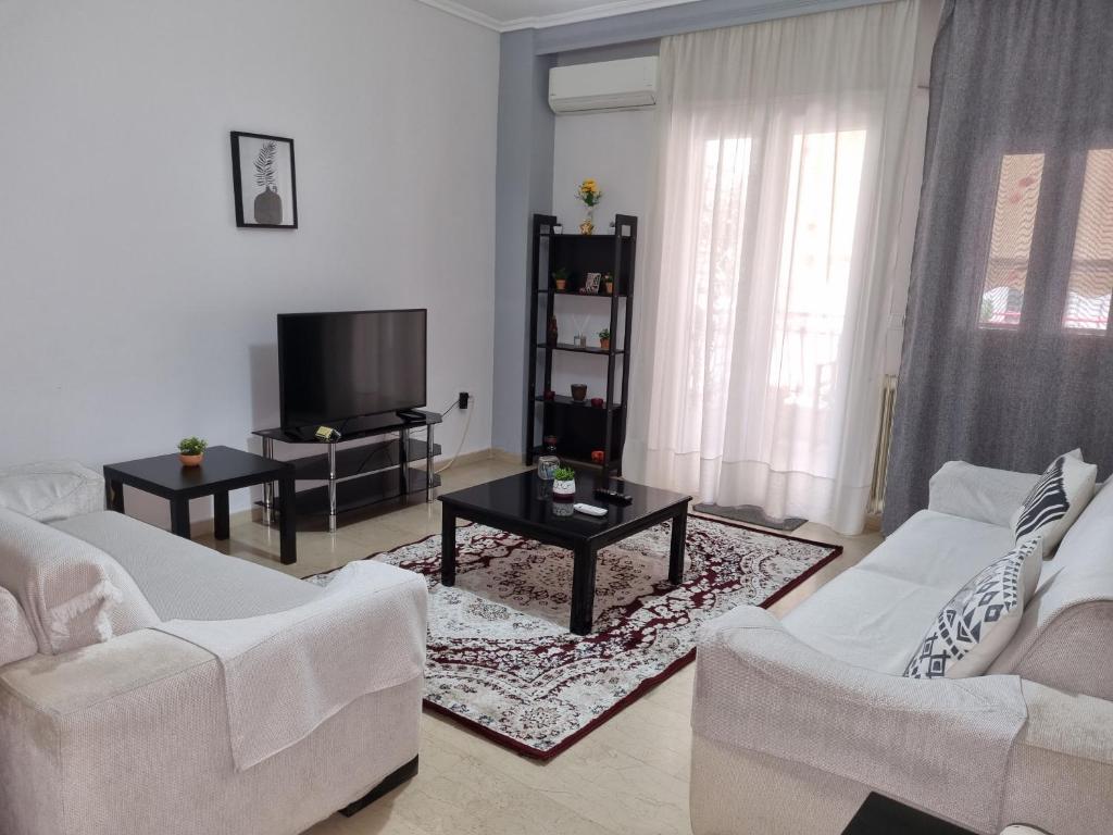 ein Wohnzimmer mit 2 weißen Sofas und einem TV in der Unterkunft Marie claire home -Private parking in Thessaloniki