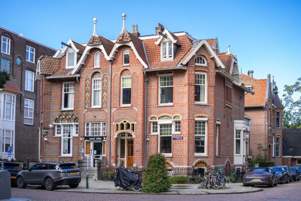 a large brick building with cars parked in front of it at Hotel Atlas Vondelpark in Amsterdam