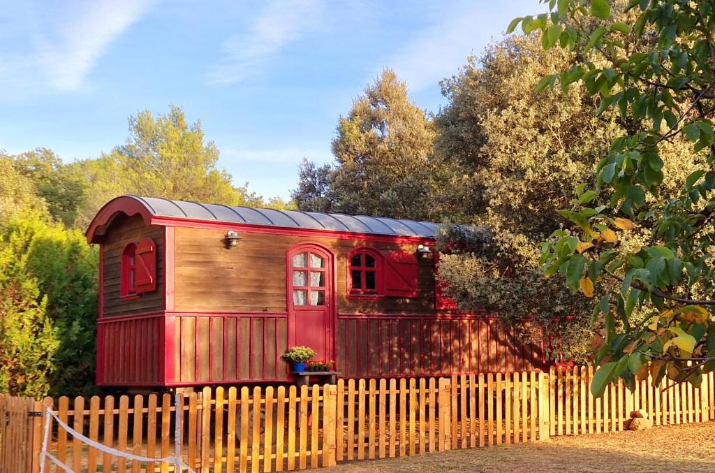 a red and wooden house behind a fence at Chambre in Jouques