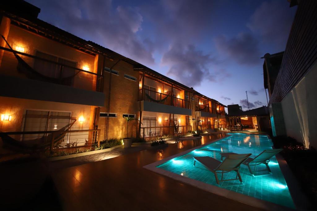 a building with a swimming pool at night at Uri Pousada in Maragogi