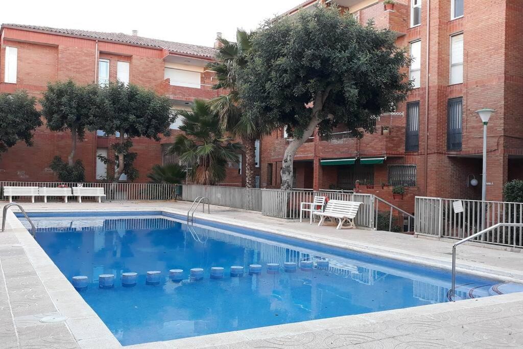 a large blue swimming pool in front of a building at Apartamento acogedor in El Vendrell