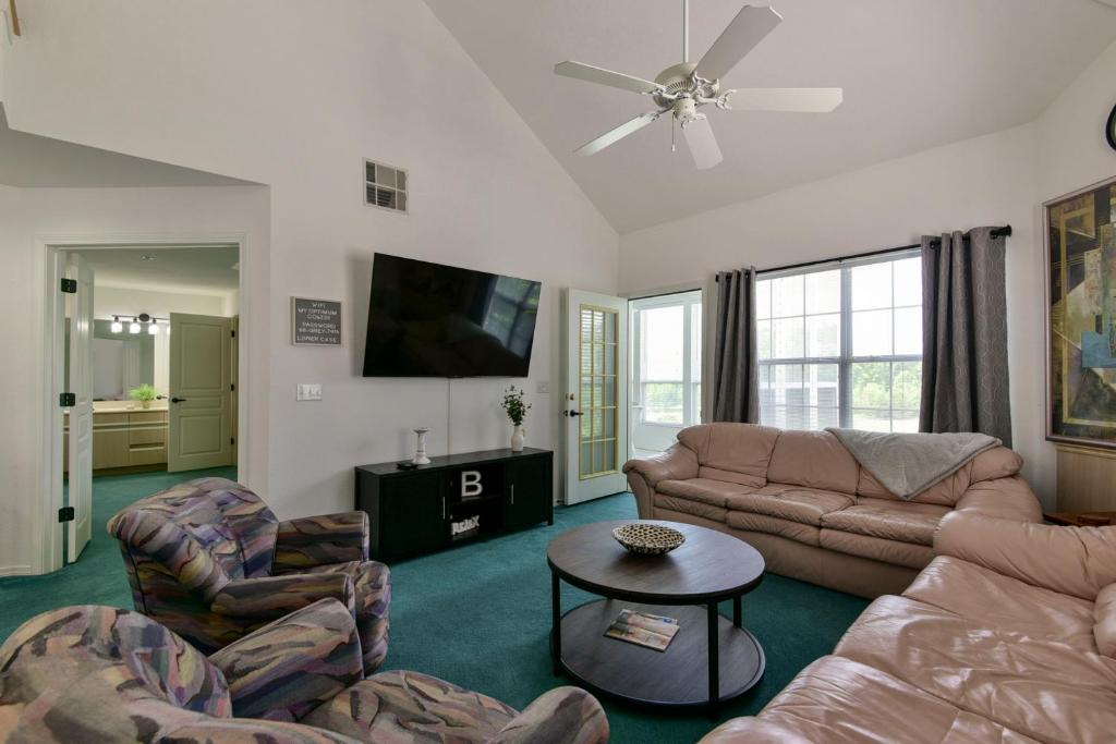 ein Wohnzimmer mit einem Sofa, Stühlen und einem TV in der Unterkunft Gorgeous Condos at Thousand Hills - Heart of Branson - Spacious and Affordable in Branson