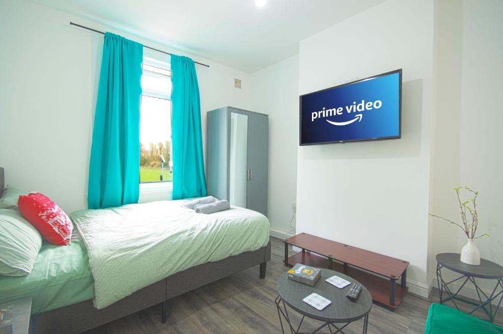Un dormitorio con una cama y un televisor en la pared. en Cosy family home w/Wi-Fi, parking, self check-in, en Londres